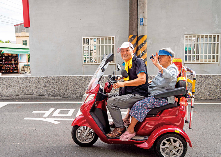 104歲的失智阿嬤許吳笑（右），到現在還能自己爬上機車， 請兒子帶她到據點參與活動。