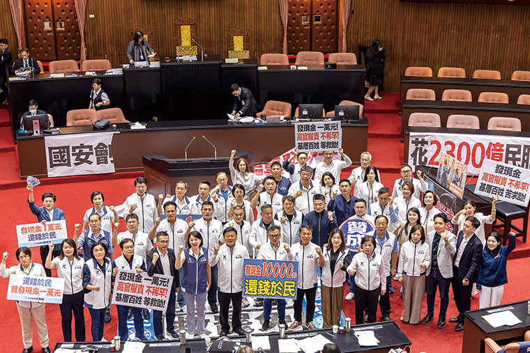藍白立委身穿白衣在議場高喊「還稅於民」，力挺發現金一萬元，舉 牌批評政府財政分配不公，主張將超徵稅收返還全民。