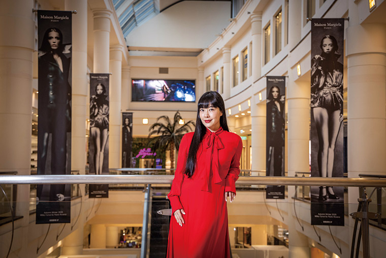 微風集團策略長廖曉喬站在國際精品樓層，身後是最新引進、全台獨家 的法國設計師品牌「Maison Margiela」的巨幅廣告垂簾，拚勁十足。
