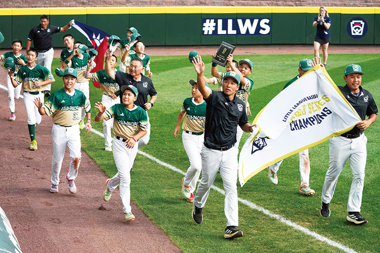 東園國小奪冠後,由兩名年輕教練駱政宇(右2)和藍振奕(右1) 舉起冠軍旗幟,率全隊繞場致意。