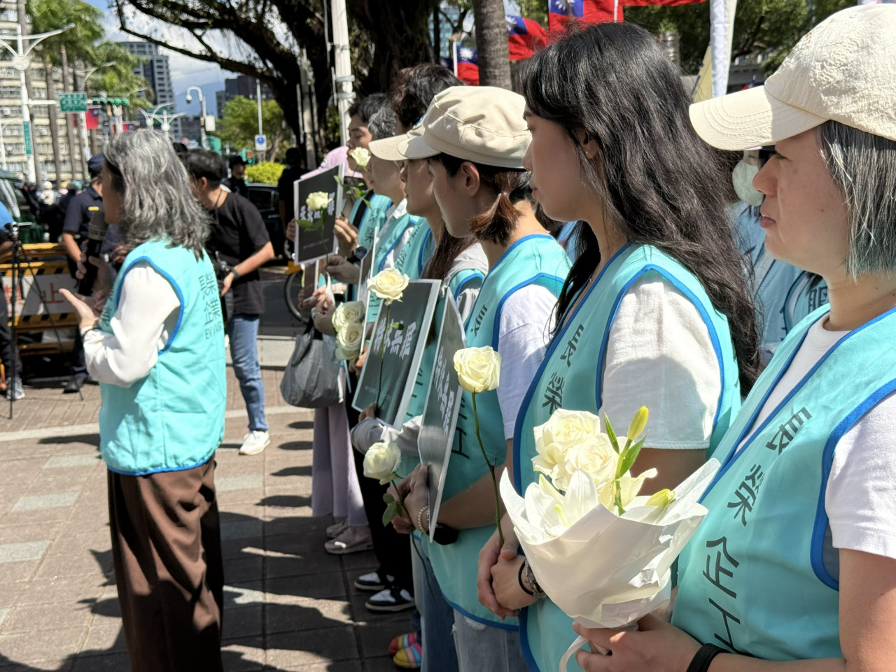 許多現役空服員手持白花，在立法院前替死者哀悼。