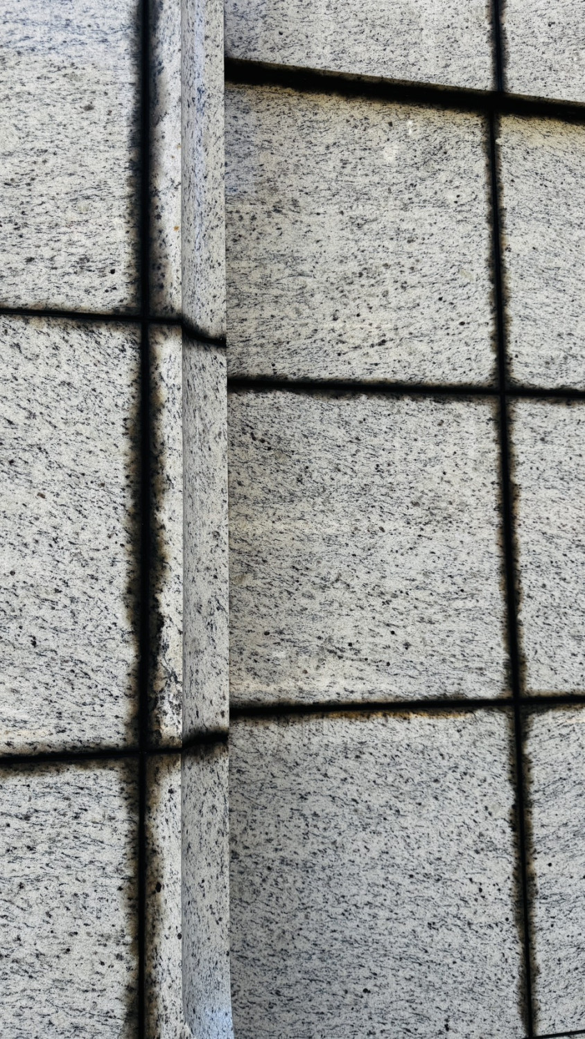 漸層線條 常出現在花崗石牆面,縫隙處有不均勻的黑色線條。這是石材與石材間的填縫材或矽利康發生質變,油性滲出並被石材的孔隙吸收,原本整齊劃一的線條變成不規則的毛邊感。